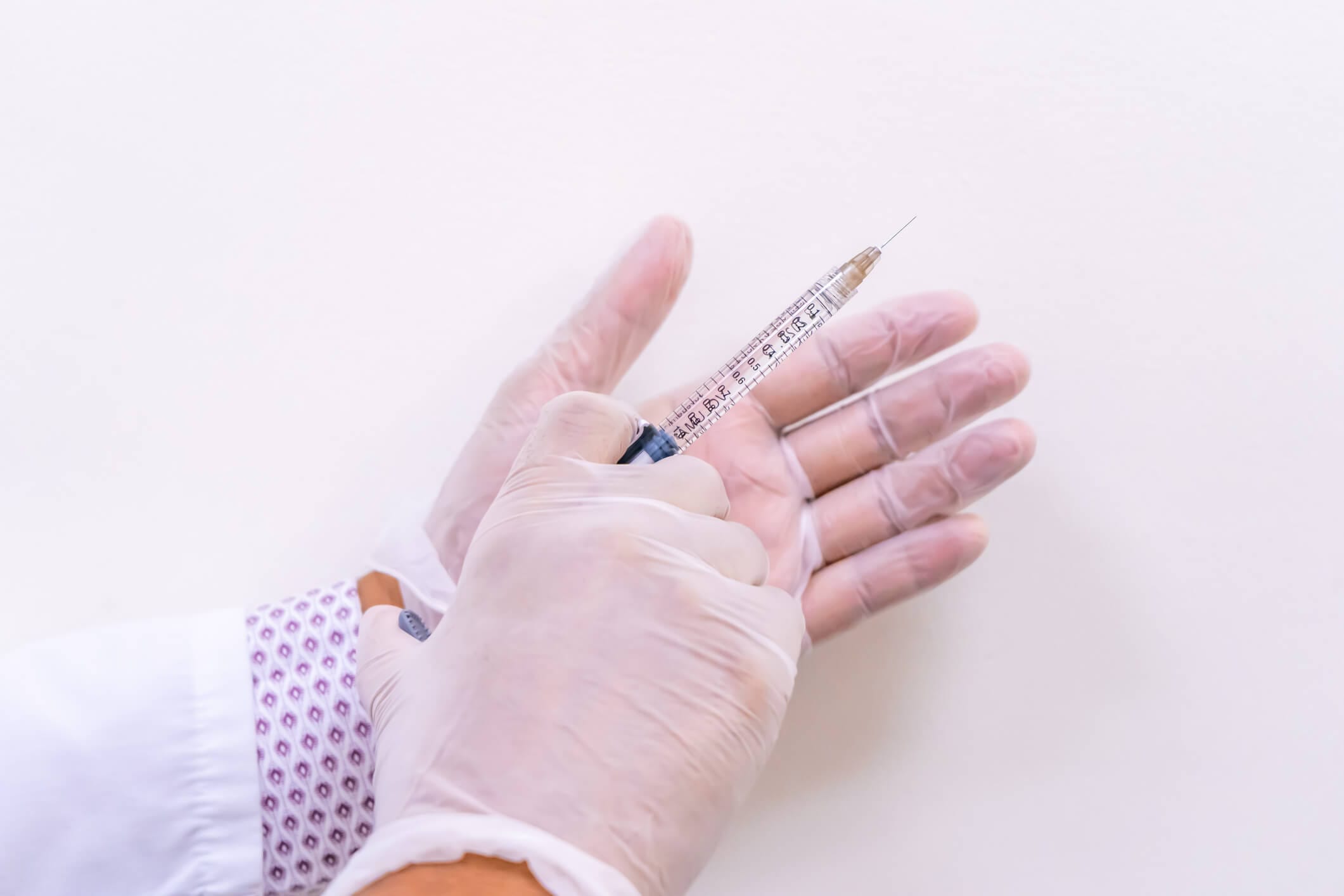 Surgeon holding a syringe, poised to combat aging using Juvéderm Voluma in Newport Beach, California at Dr. George Brennan Clinic