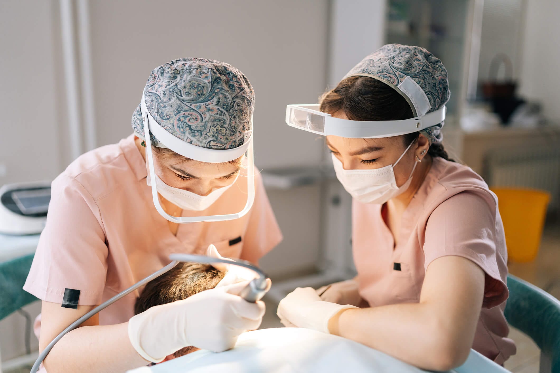 Two healthcare professionals perform neograft procedure to address hair loss, using medical equipment on a patient lying on a table in Newport Beach, California